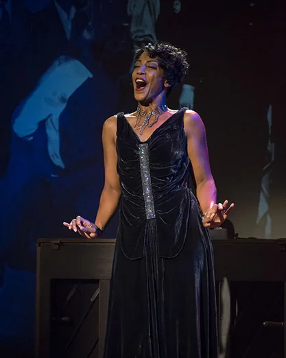 Yvette Spears singing on stage in a black gown
